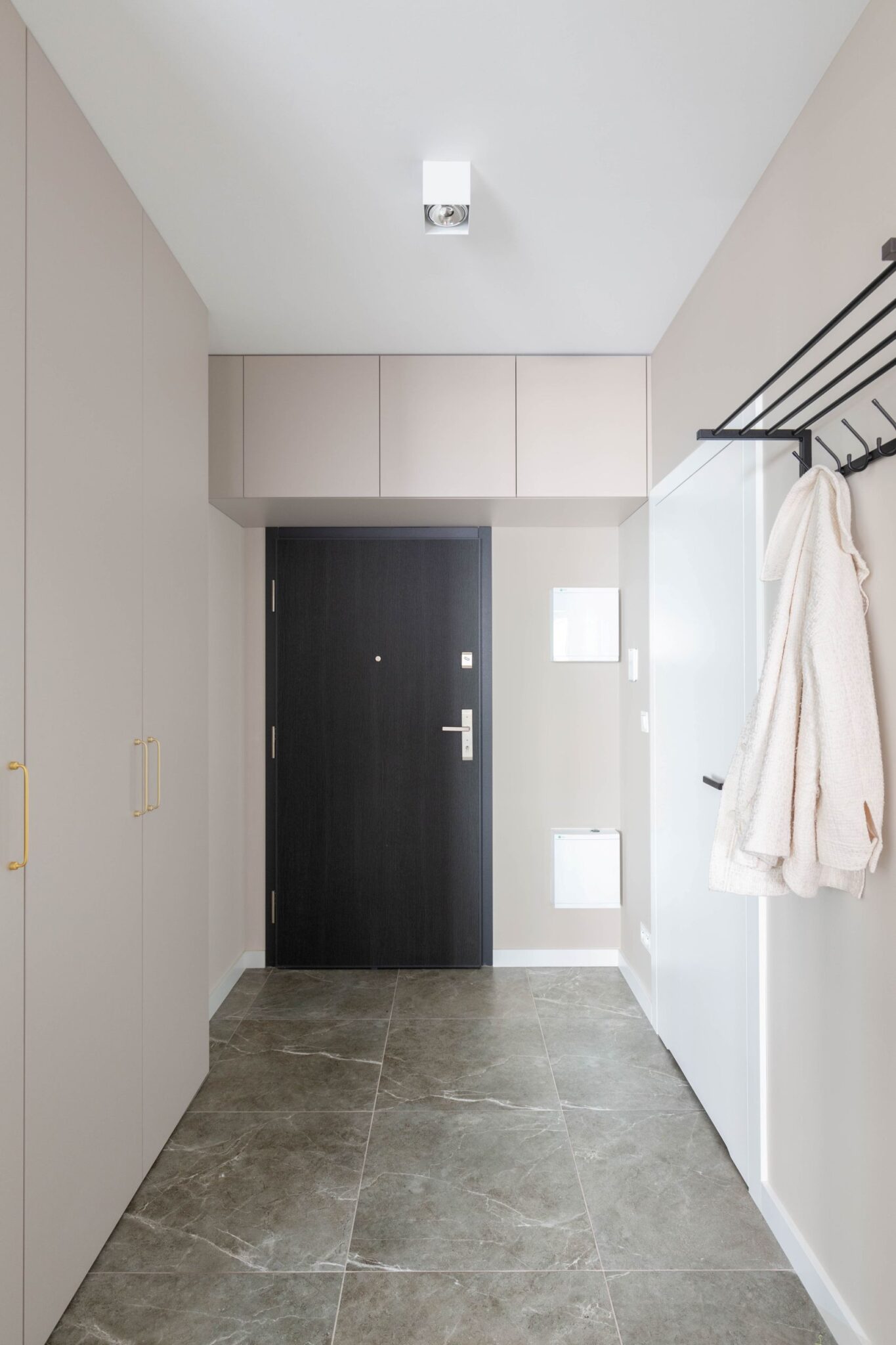 Ciemne drzwi wejściowe i jasne ściany - aranżacja.